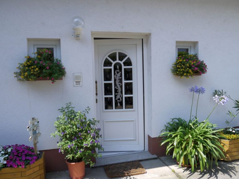 Hauseingang mit weißer Tür und Blumenkästen