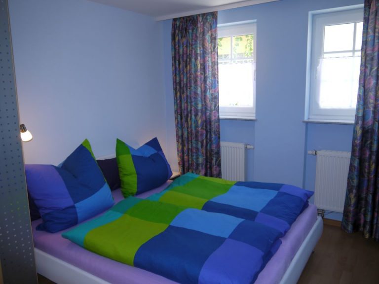Schlafzimmer mit blau-grüner Bettwäsche