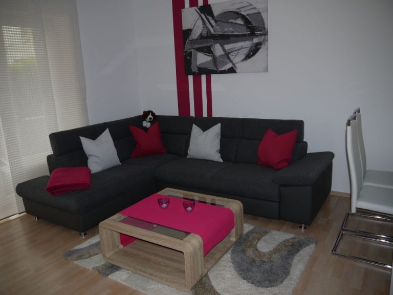 Wohnzimmer mit dunkler Couch und bunten Kissen