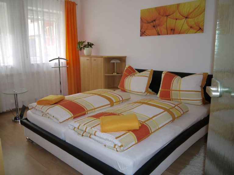 Schlafzimmer mit orangefarbener Bettwäsche